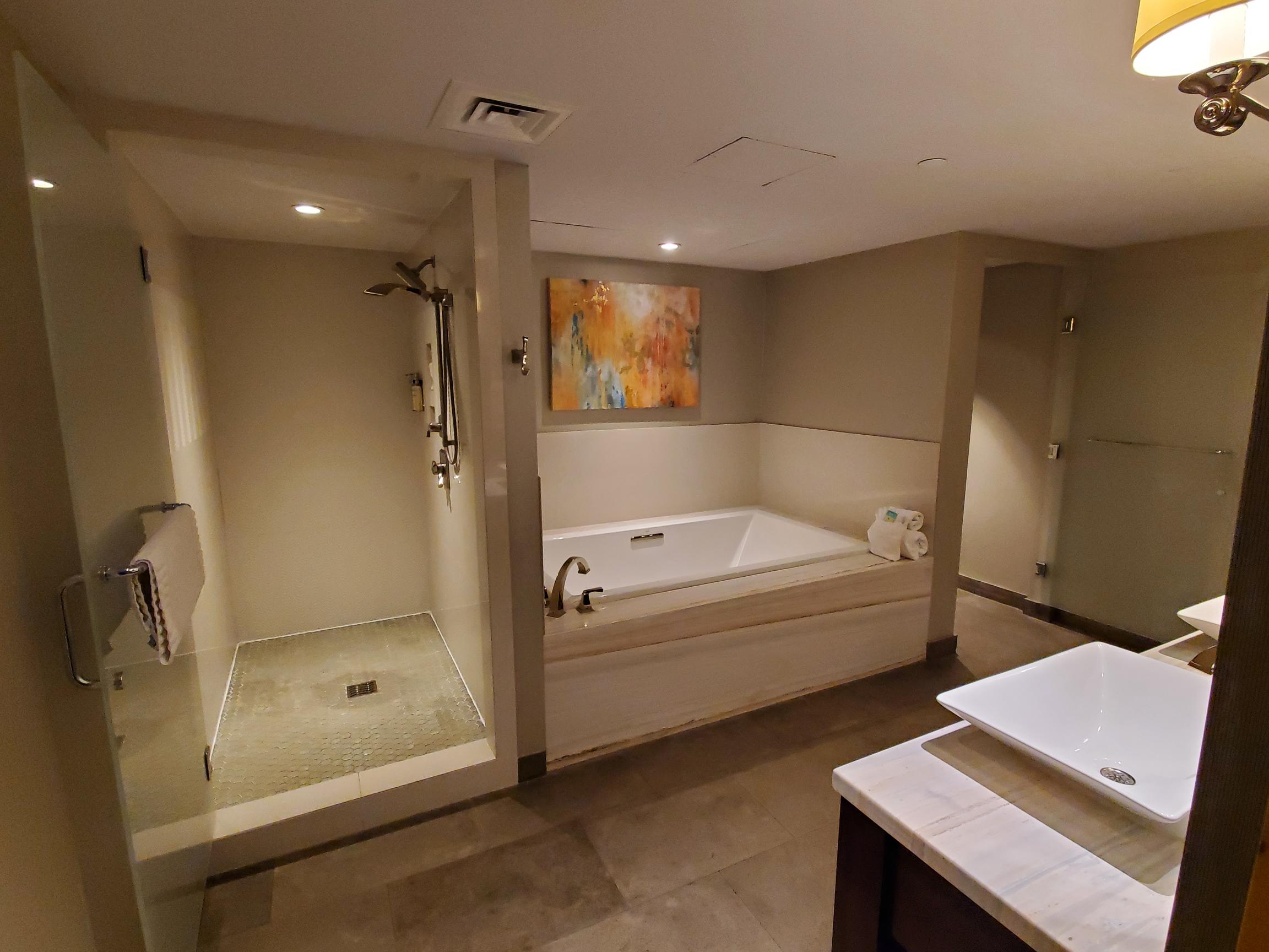 A bathroom with a large soaking tub, separate shower, and single sink