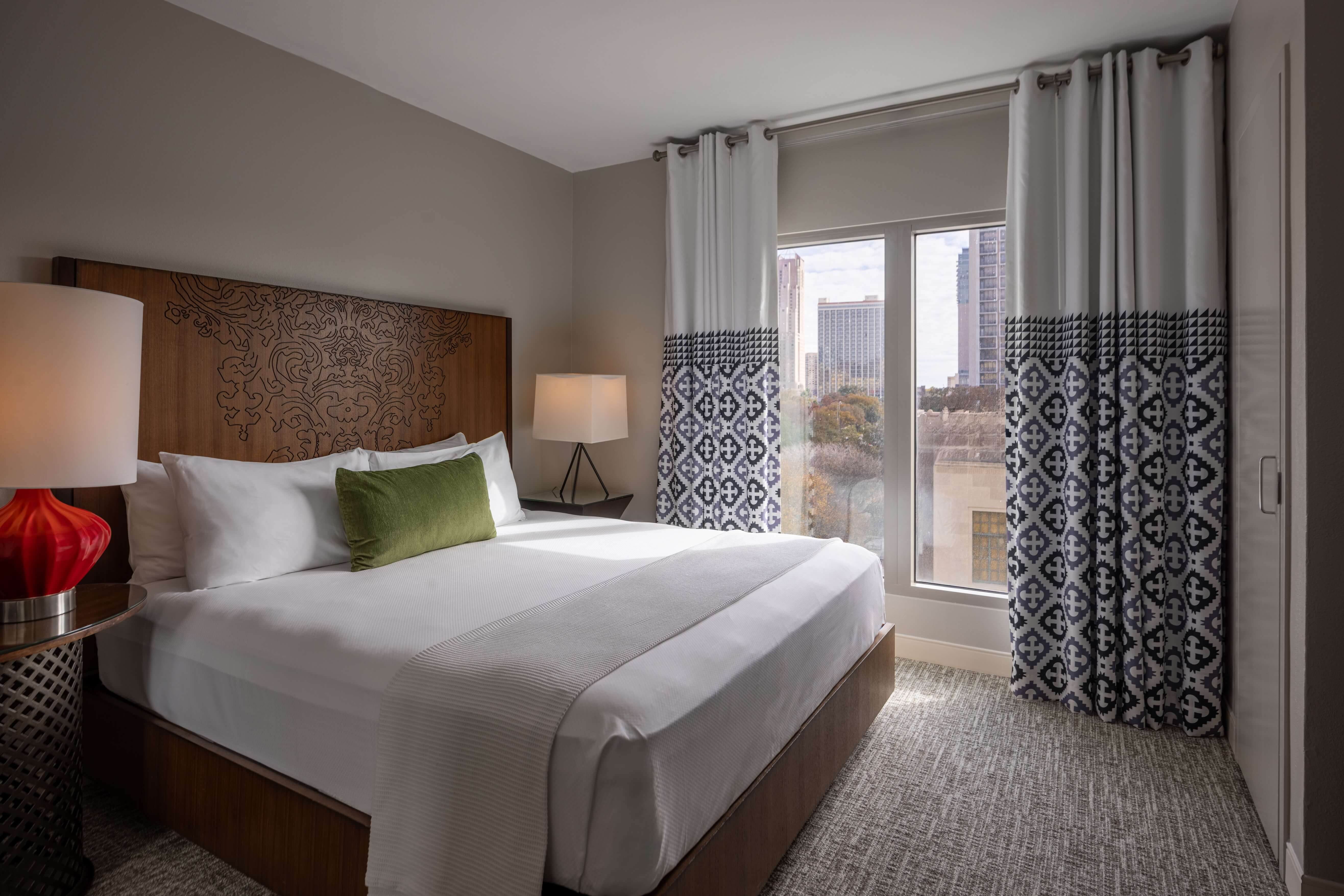 A hotel room with a large bed, wooden headboard, and city view.